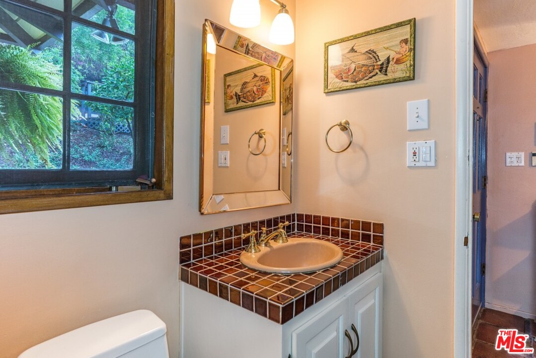 3266 Mandeville Canyon Road Los Angeles, CA 90049 - Photo 21 of 37 a bathroom with a granite countertop sink and a toilet