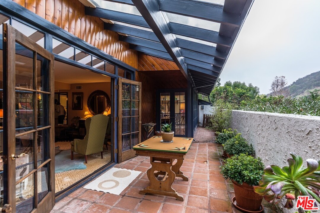 3266 Mandeville Canyon Road Los Angeles, CA 90049 - Photo 5 of 37 a view of a patio with table and chairs potted plants with wooden floor and fence