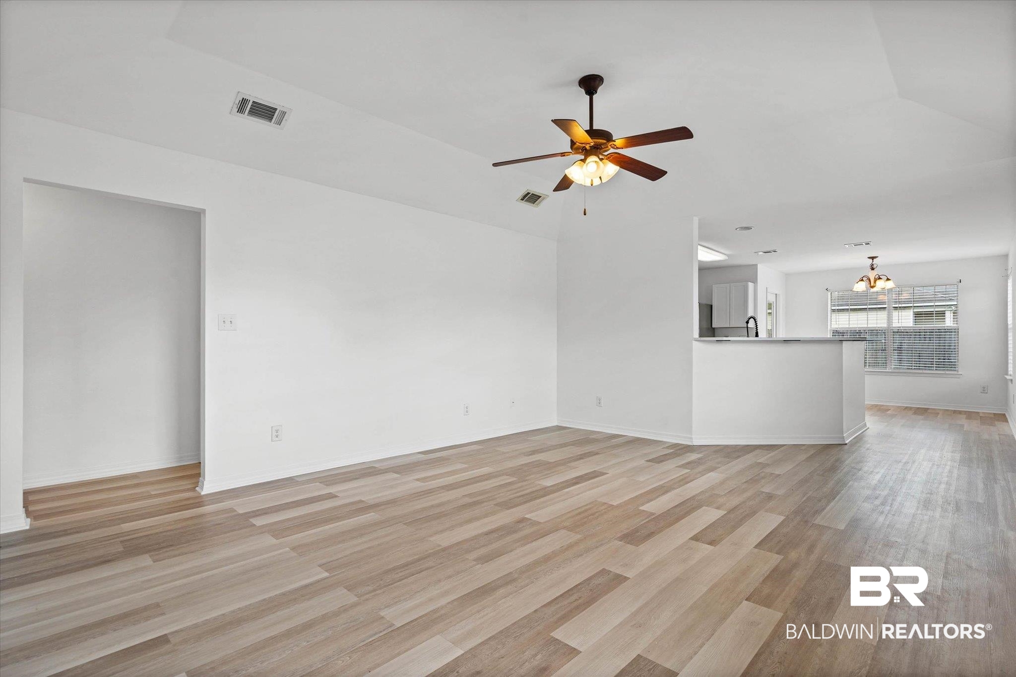 8980 Spring Grove North Mobile, AL 36695 - Photo 2 of 24 Open concept living space featuring wood-finish flooring, a ceiling fan with integrated lighting, and a partial wall with a stone-look countertop