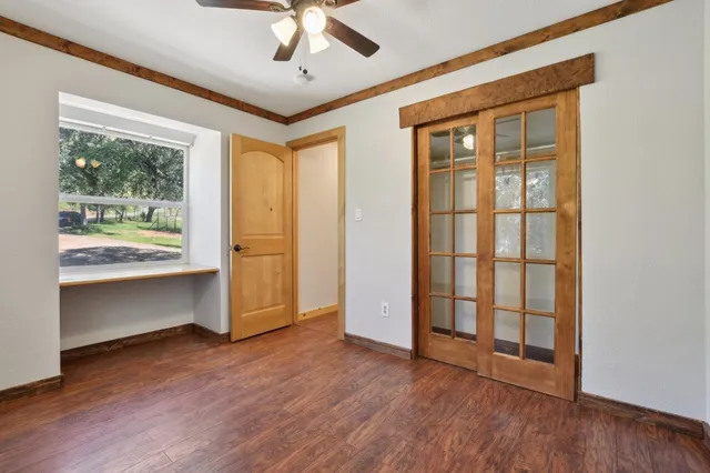 a view of an empty room with a window and wooden floor