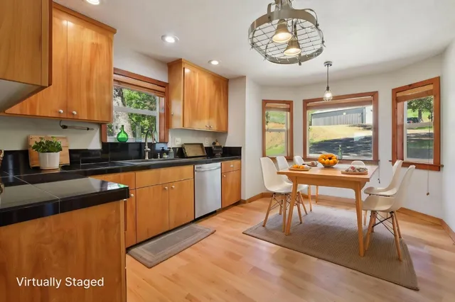 a kitchen with stainless steel appliances granite countertop a stove top oven a sink dishwasher a dining table and chairs with wooden floor