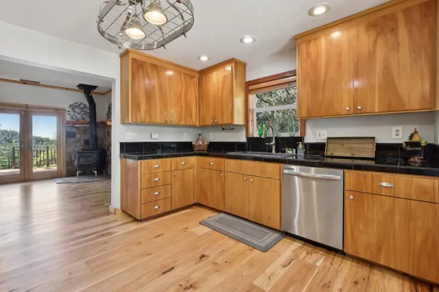 a kitchen with stainless steel appliances granite countertop wooden cabinets a stove a sink and dishwasher with wooden floor