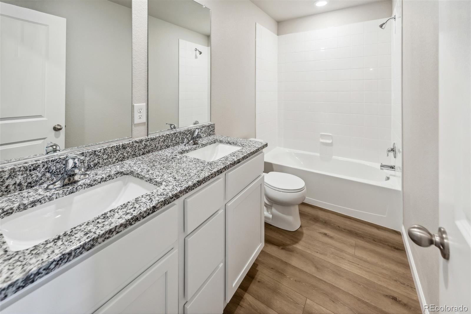 2220 Christina Street Fort Lupton, CO 80621 - Photo 19 of 42 a bathroom with a granite countertop sink a toilet and shower