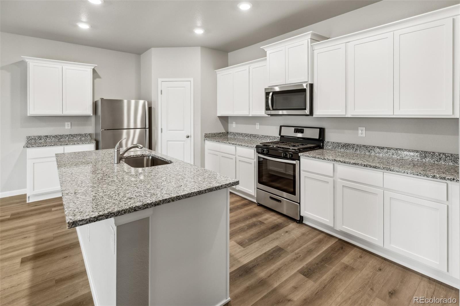 2220 Christina Street Fort Lupton, CO 80621 - Photo 3 of 42 a kitchen with granite countertop white cabinets and stainless steel appliances