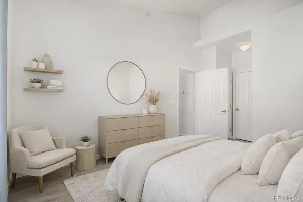 a bedroom with a bed a couch and a potted plant on the dresser