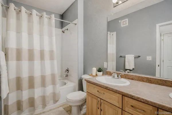 a bathroom with a granite countertop sink a toilet and a large mirror