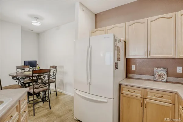 a white kitchen with stainless steel appliances a refrigerator and a stove top oven