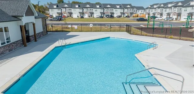 a view of a swimming pool with a lawn chairs and floor to ceiling window