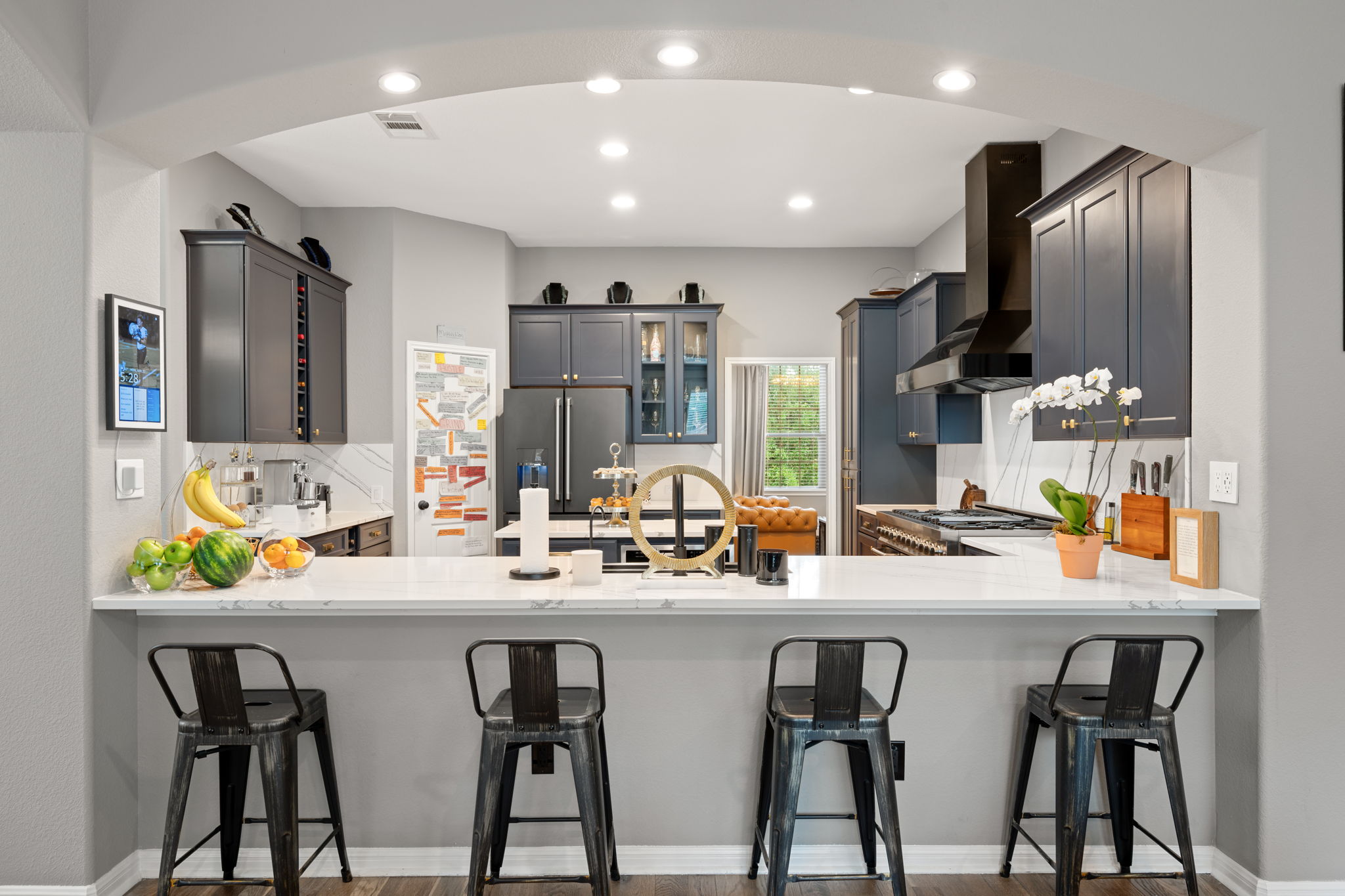12109 Montclair Bend Austin, TX 78732 - Photo 12 of 39 Kitchen featuring a white countertop with integrated bar seating, recessed lighting, dark cabinetry, and a black range hood