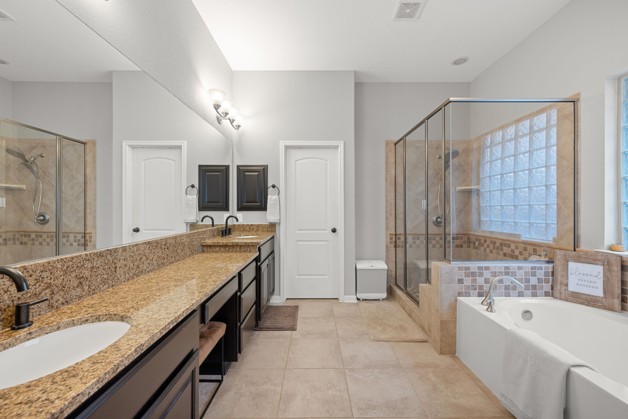 12109 Montclair Bend Austin, TX 78732 - Photo 18 of 39 Spacious bathroom featuring a dual vanity with granite countertops, integrated sinks, and dark wood cabinetry