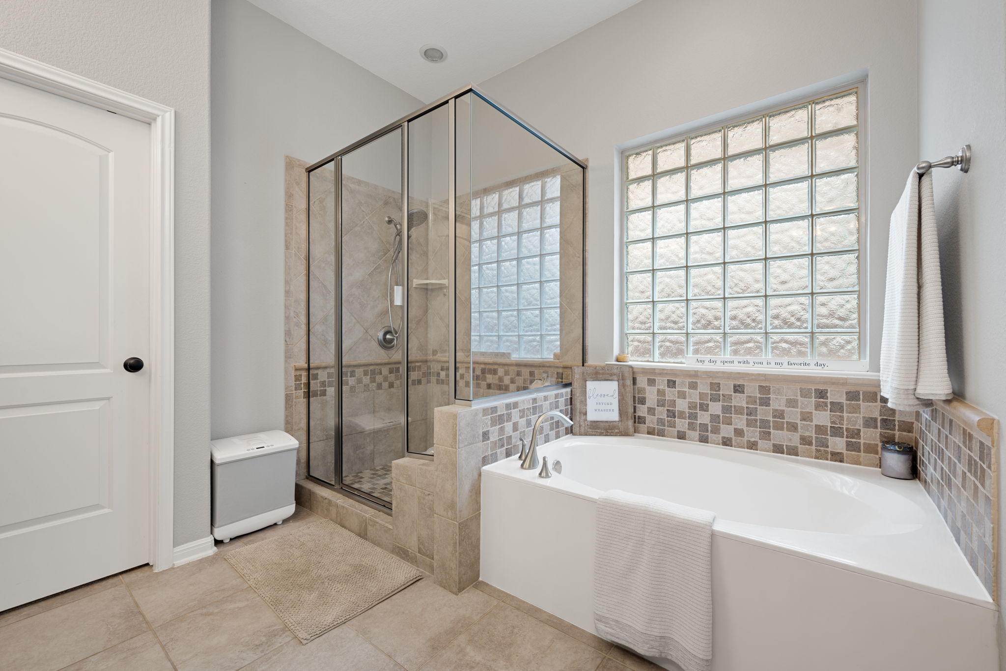 12109 Montclair Bend Austin, TX 78732 - Photo 19 of 39 Spacious bathroom featuring a glass-enclosed shower with tiled walls, an integrated bench, and a privacy glass block window