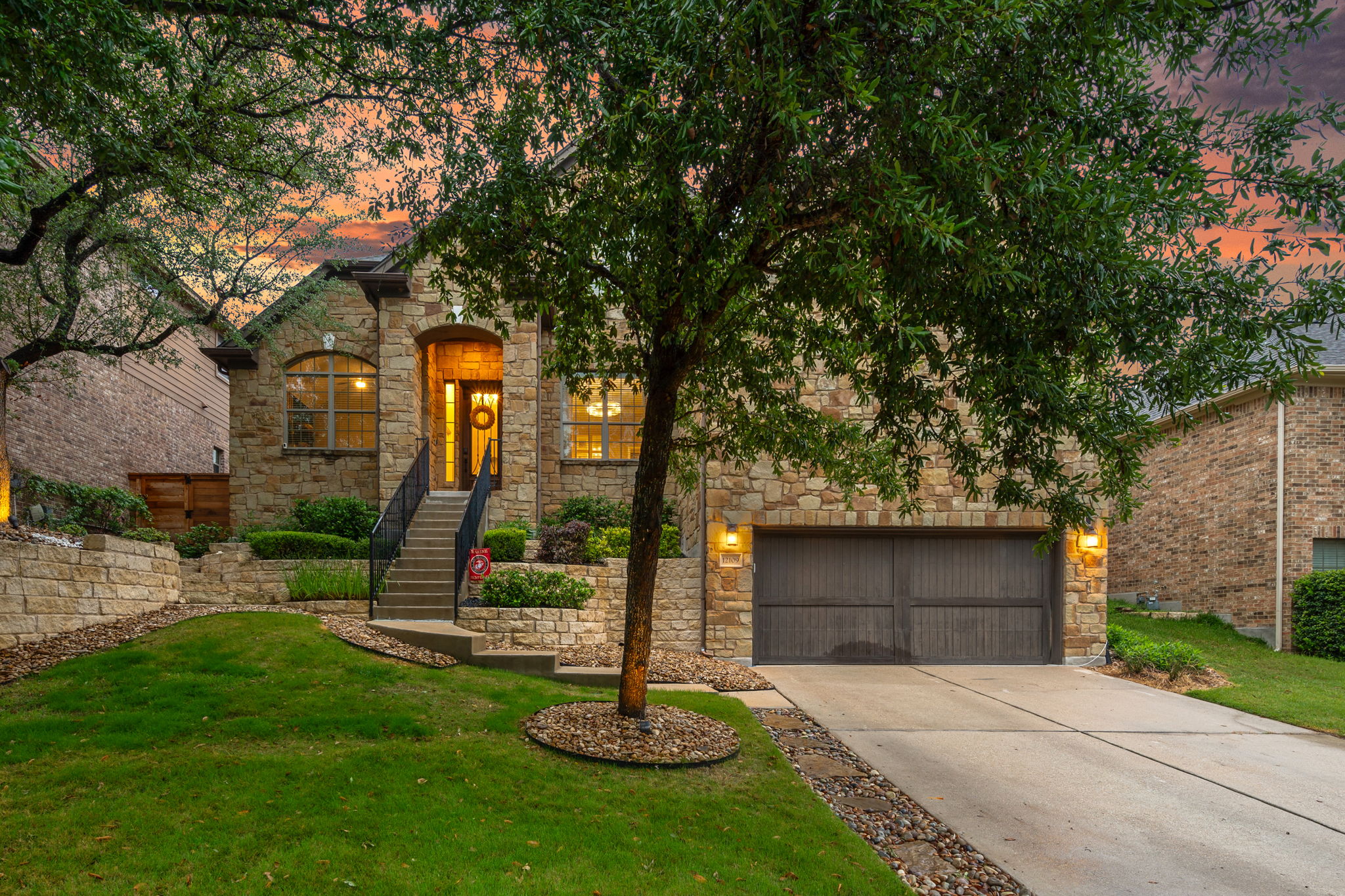 12109 Montclair Bend Austin, TX 78732 - Photo 2 of 39 Stone facade residence featuring an arched entry, a two-car garage, and established landscaping
