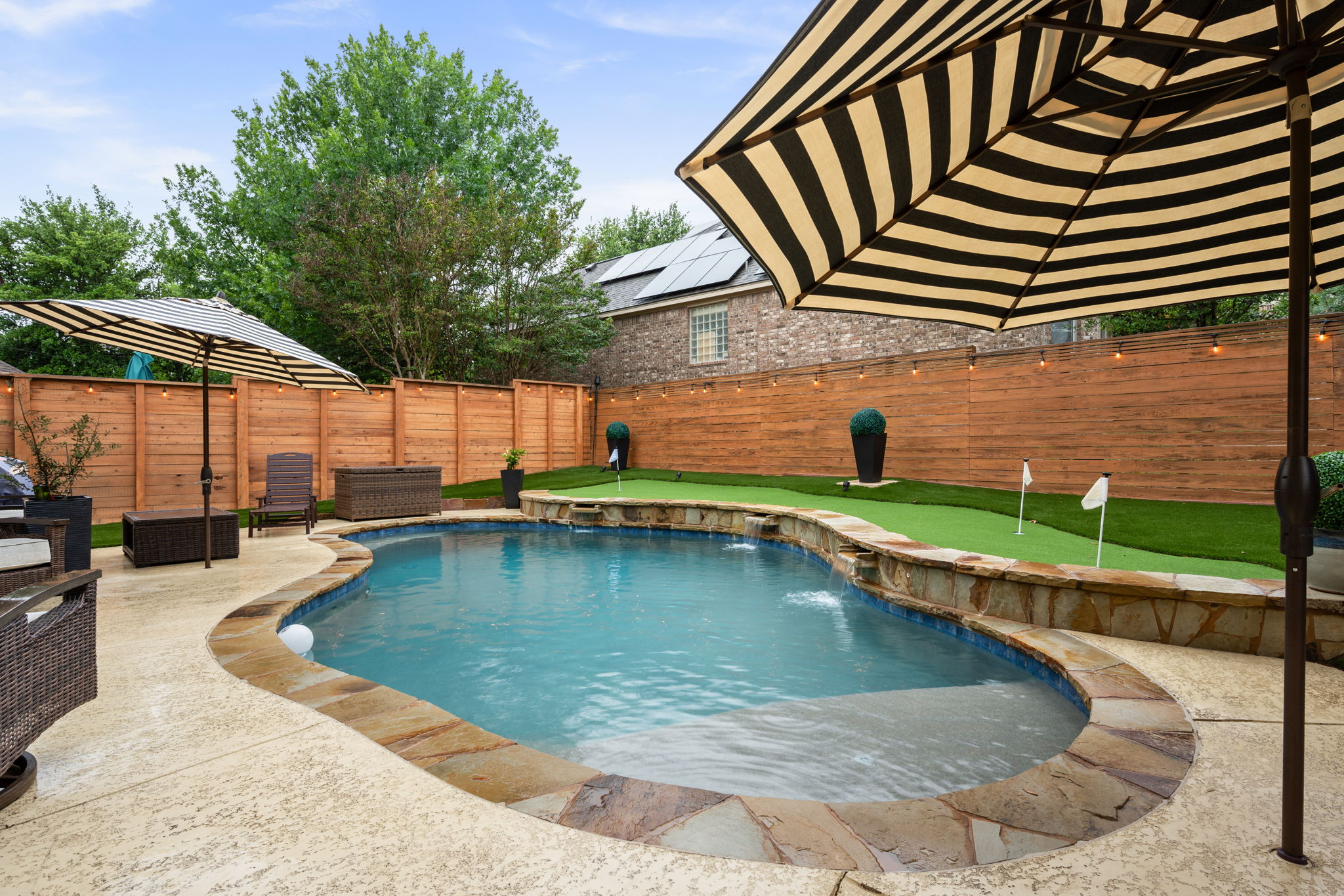 12109 Montclair Bend Austin, TX 78732 - Photo 33 of 39 Curved swimming pool featuring a stone-faced waterfall and integrated steps