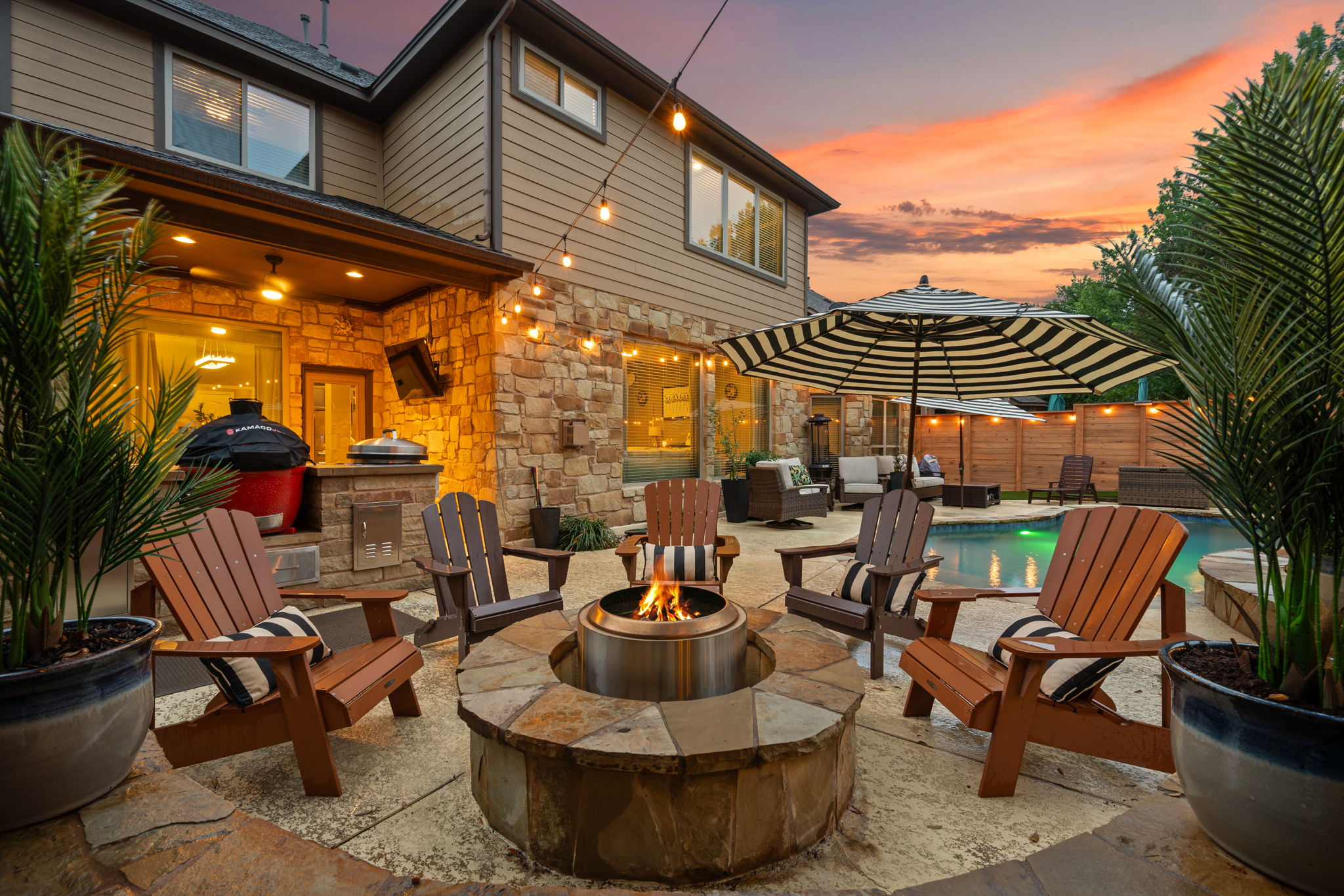 12109 Montclair Bend Austin, TX 78732 - Photo 35 of 39 Expansive stone patio featuring a built-in fire pit, outdoor kitchen with stone surround, and an integrated swimming pool