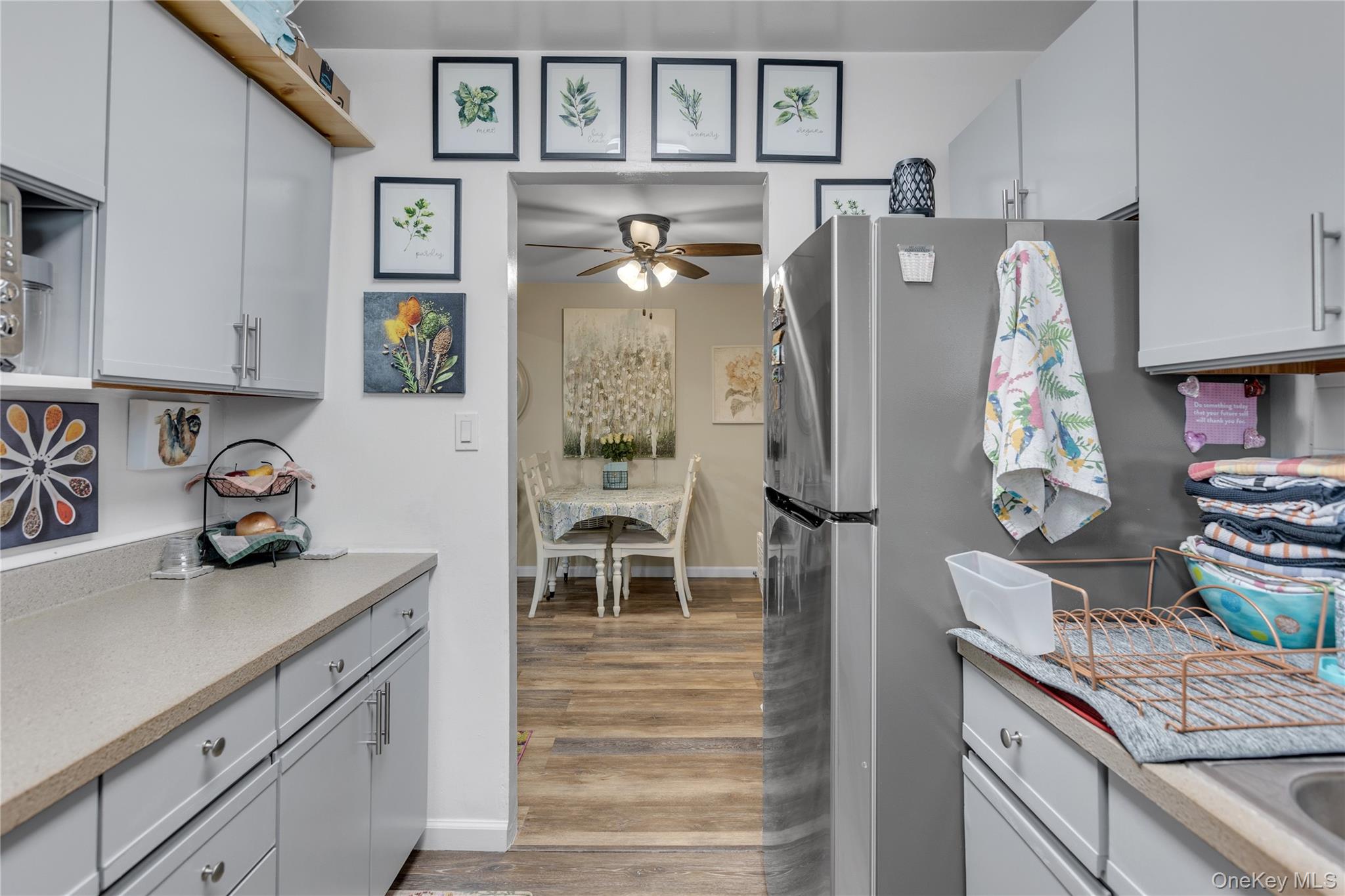 200 Merrick Road, Unit I Amityville, NY 11701 - Photo 6 of 12 Kitchen featuring light countertops, freestanding refrigerator, light wood finished floors, gray cabinets, and ceiling fan