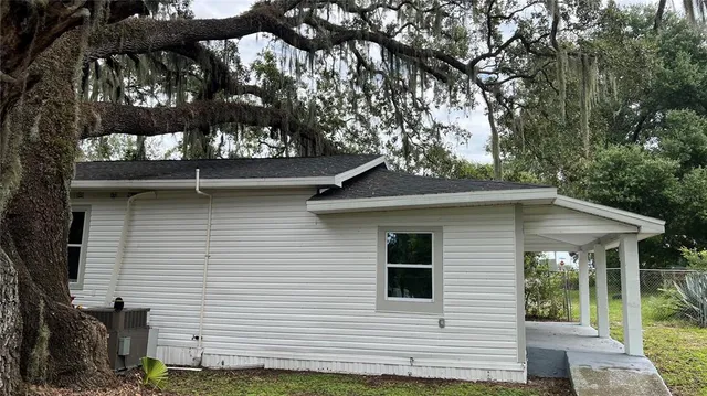 a backyard of a house with large trees and table and chairs