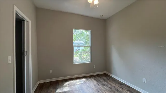 an empty room with wooden floor cabinet and windows