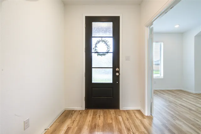 a view of a hallway with wooden floor and a bathroom