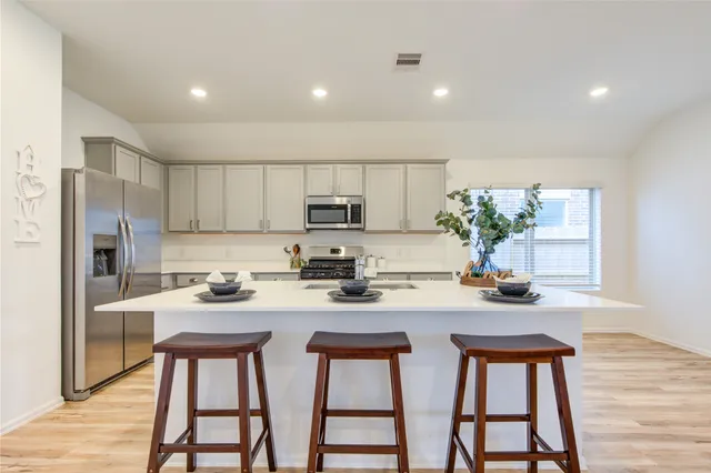 a kitchen with stainless steel appliances a table chairs refrigerator and microwave