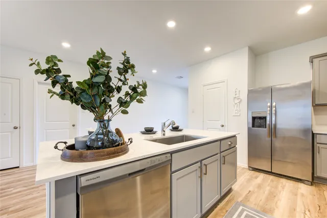 a kitchen with stainless steel appliances a sink a potted plant and a counter space