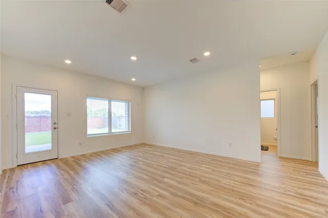 an empty room with wooden floor and windows