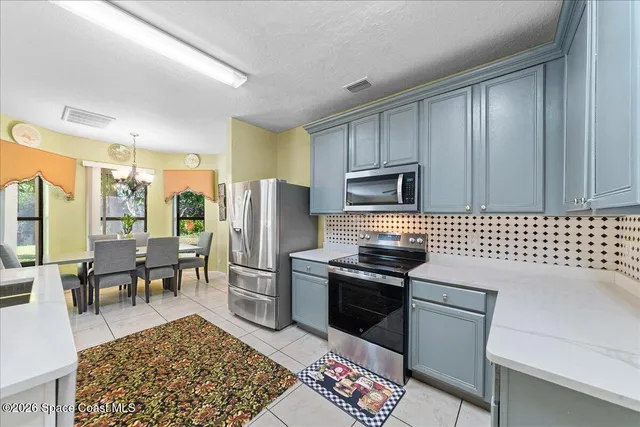 a kitchen with granite countertop a refrigerator stove top oven dining table and chairs