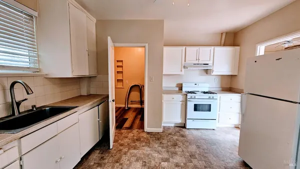 a kitchen with stainless steel appliances granite countertop a refrigerator sink stove and white cabinets