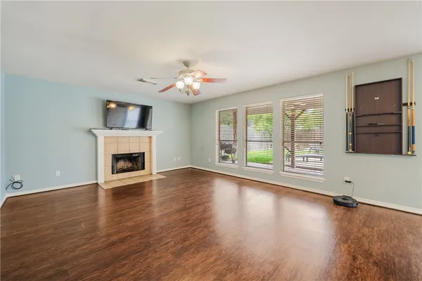 an empty room with windows fireplace and wooden floor