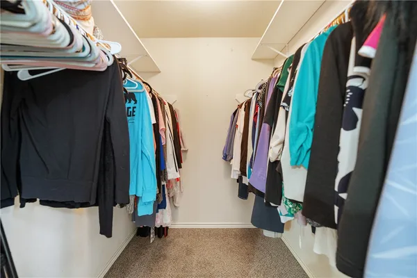a view of walk in closet with clothes and shoes