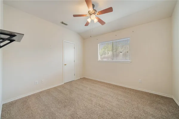 an empty room with a window and a fan
