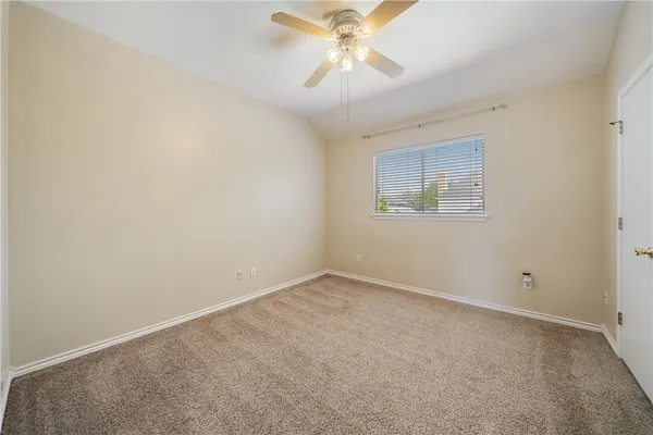 an empty room with a chandelier fan and windows