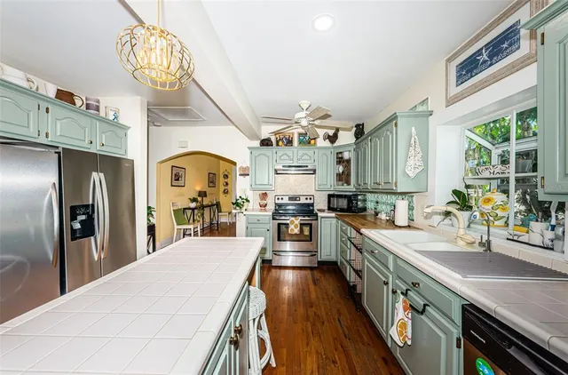 a large kitchen with stainless steel appliances kitchen island a large counter space a large window and stainless steel appliances