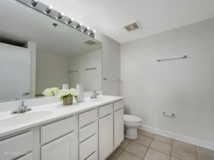 a spacious bathroom with a granite countertop sink a toilet and a mirror