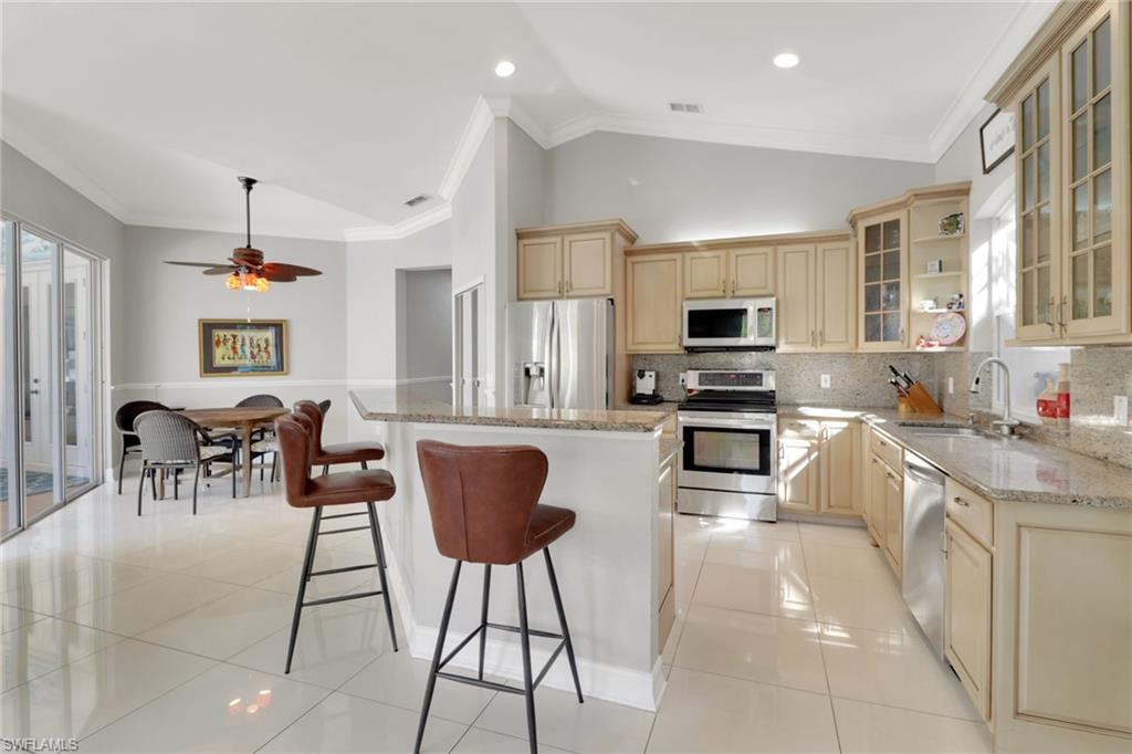 4380 7th Avenue Southwest Naples, FL 34119 - Photo 15 of 39 a kitchen with stainless steel appliances granite countertop a stove top oven a sink a dining table and chairs