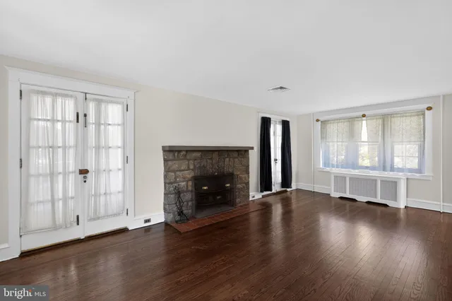 an empty room with wooden floor fireplace and windows