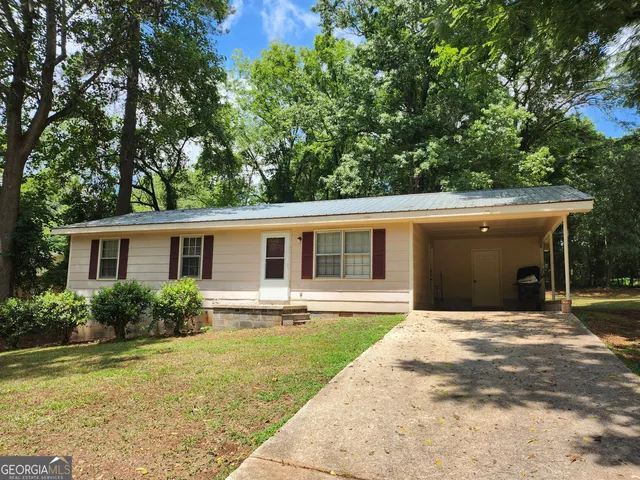 a front view of house with yard and trees in the background