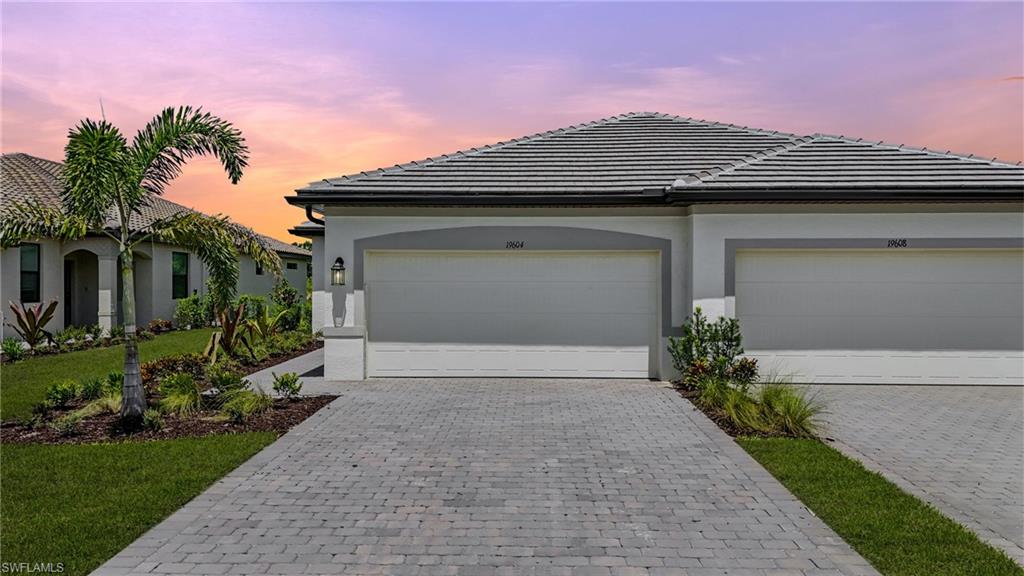 View of front facade with a tiled roof, decorative driveway, and stucco siding