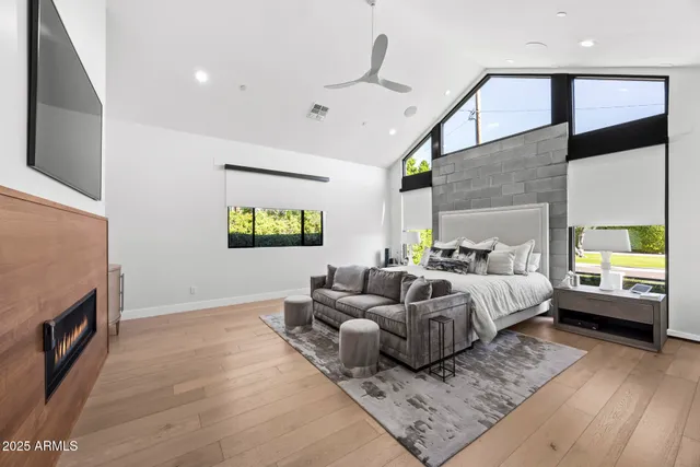a spacious bedroom with a bed a couch and a flat tv screen on the dresser