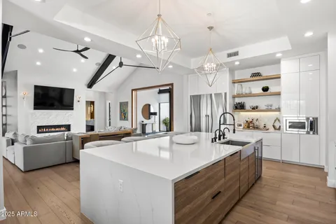 a large kitchen with stainless steel appliances kitchen island granite countertop a large island a stove a refrigerator a sink dishwasher a dining table and chairs with wooden floor