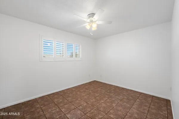 an empty room with a chandelier fan and windows