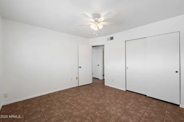 an empty room with a chandelier fan and closet area