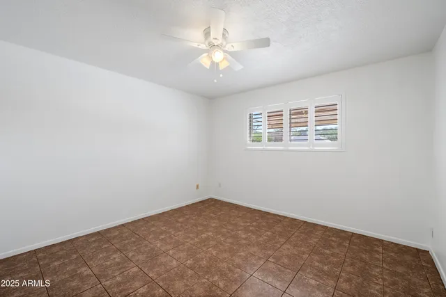 an empty room with a chandelier fan and windows