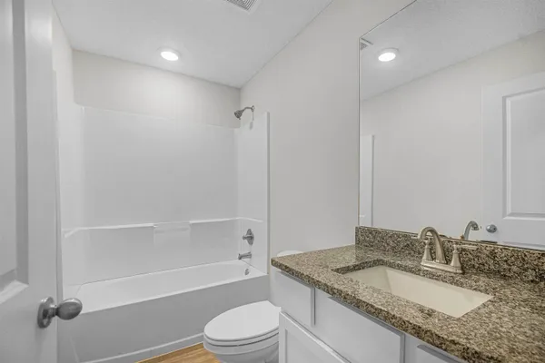 a bathroom with a granite countertop sink a toilet and bathtub