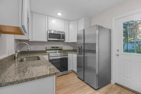 a kitchen with granite countertop a refrigerator and a sink