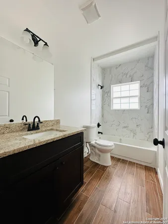 a bathroom with a granite countertop toilet a sink and a mirror