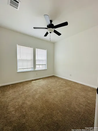 an empty room with windows and fan