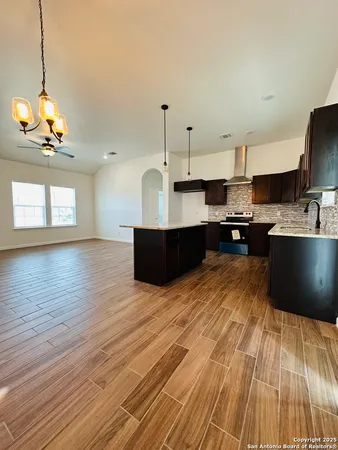 a kitchen with stainless steel appliances granite countertop a sink dishwasher a stove a dining table and chairs with wooden floor