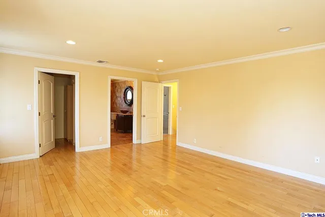 a view of an empty room with wooden floor and kitchen