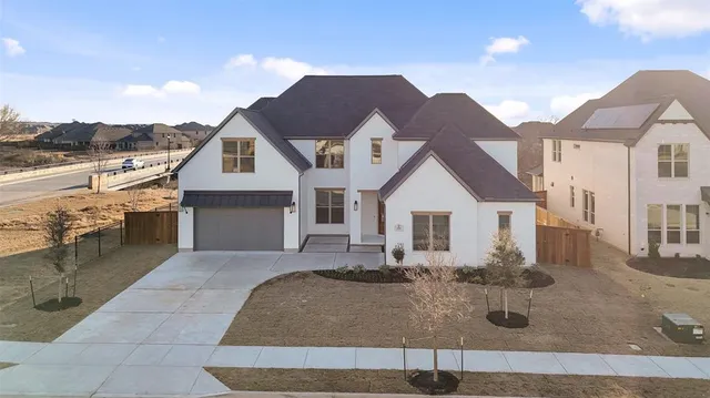 a view of a white house next to a yard with big trees