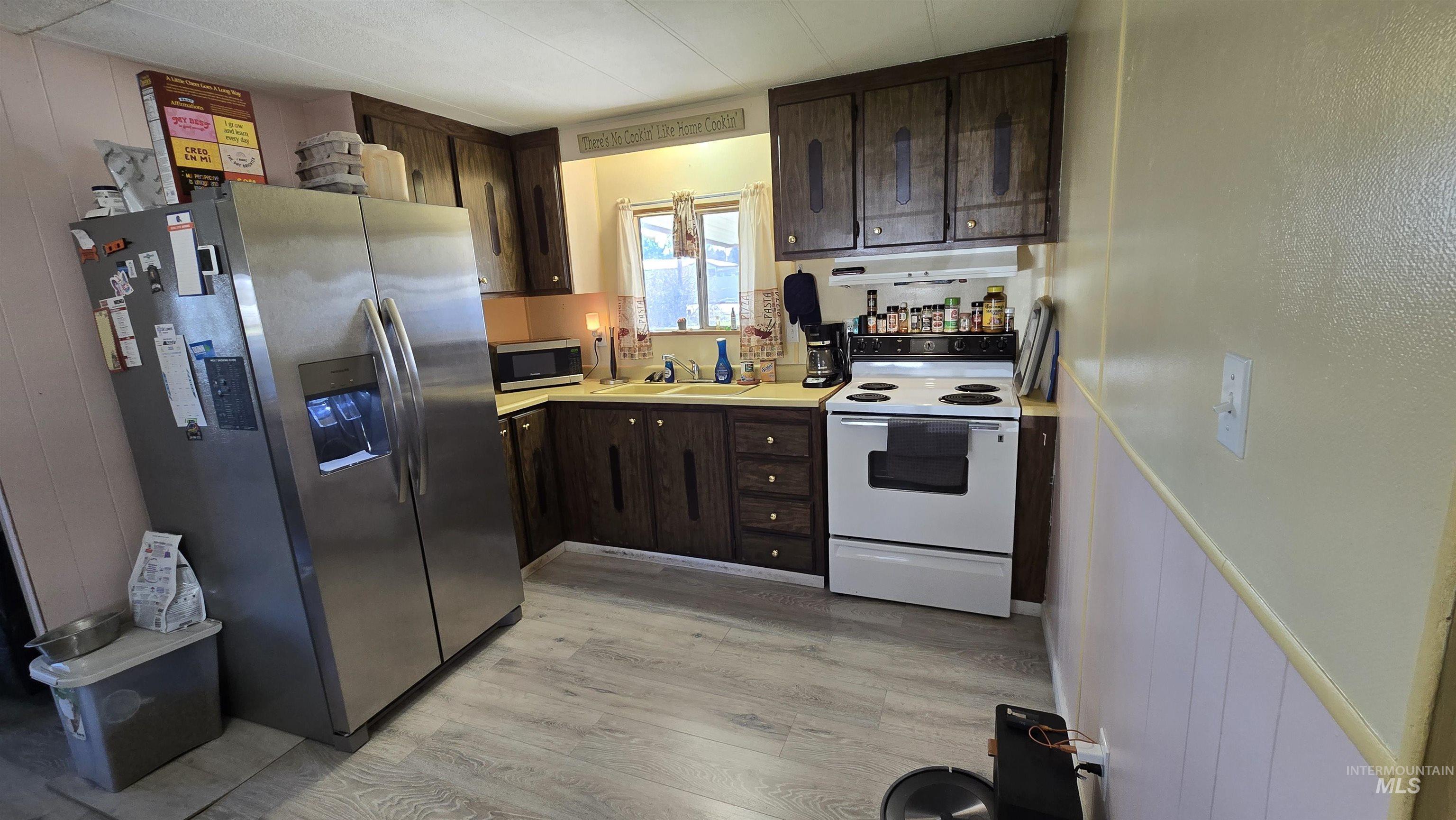 798 Dolson Lane Eagle, ID 83616 - Photo 17 of 33 Kitchen with dark wood finish cabinetry, stainless steel appliances, light countertops, light wood-style floors, and wooden walls